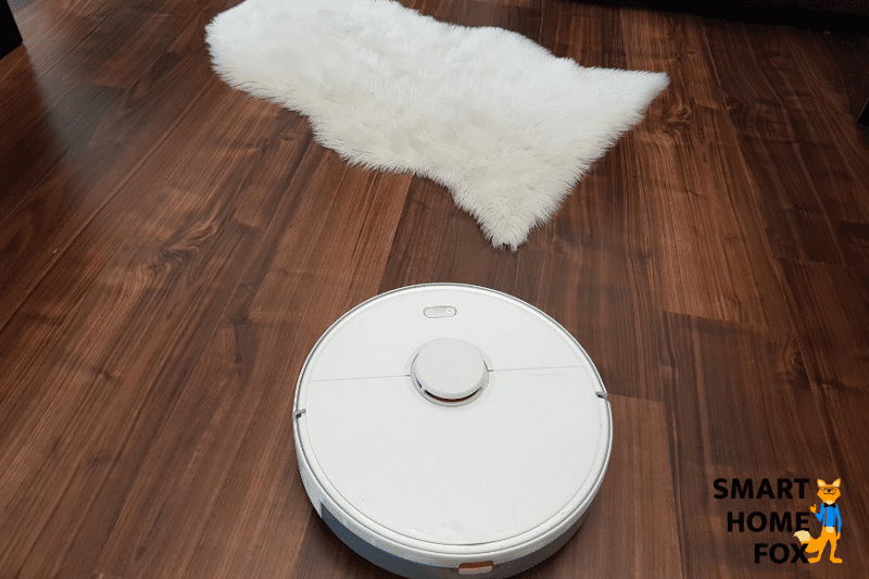 Робот-пылесос едет по паркетному полу.